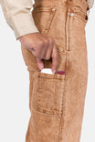 Detail view of a woman's hand reaching into the nested side pocket of Dovetail Workwear's Old School Wide Leg Jeans in Sunbaked Copper