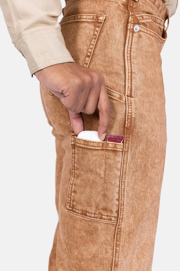 Detail view of a woman's hand reaching into the nested side pocket of Dovetail Workwear's Old School Wide Leg Jeans in Sunbaked Copper