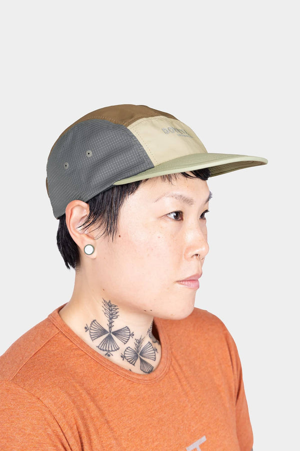 Side view of a woman wearing the Desert Tan Pack Cap, showcasing the 5-panel construction and flexible brim