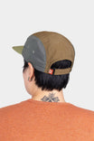 Back view of a woman wearing the Dovetail Workwear Pack Cap in Desert Tan, showcasing the adjustable back closure and side ventilation ports