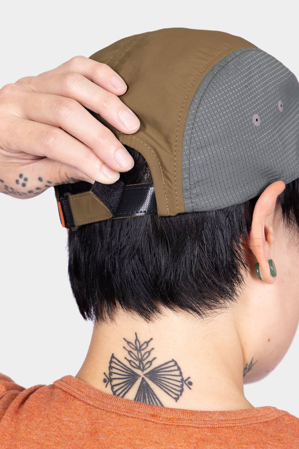 Back view of a woman wearing the Desert Tan Pack Cap, showing the adjustable back closure and side ventilation ports