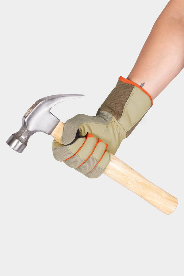 Woman wearing Dovetail Workwear Performance Work Gloves in Light Kodiak holding a claw hammer, showing the glove's grip and leather protection