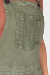 Detail shot of the bib pocket with snap closure on Dovetail Workwear's Utility Short Overalls in Light Kelp Green