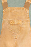 Detail shot of the Utility Short Overalls in Tan Sandstone by Dovetail Workwear, showing the bib pocket with snap closure and jacquard botanical texture print