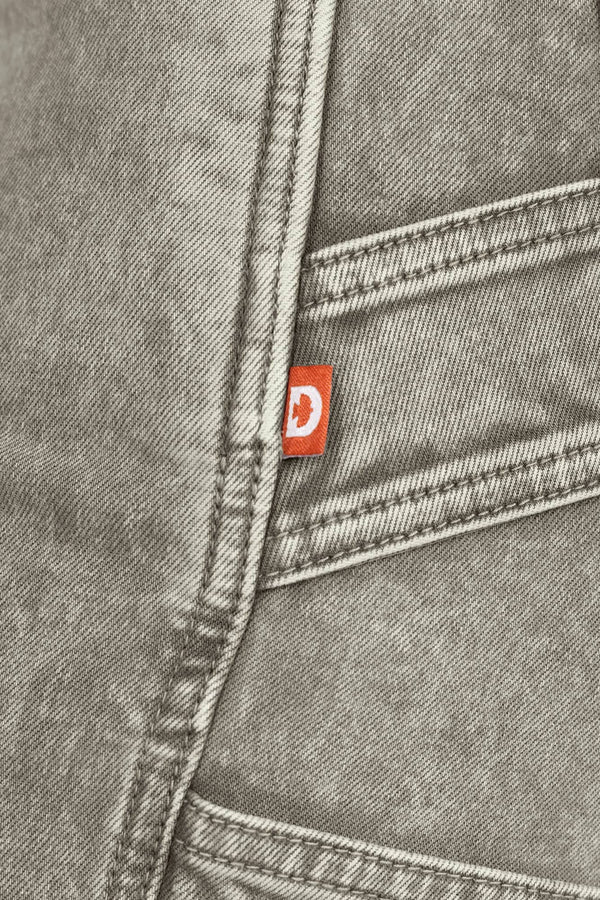 Close-up detail of the Dovetail Workwear Old School Wide Leg Mineral Wash Jeans in Sunbaked Eucalyptus, showing the nested side pocket and brand label on gray denim fabric