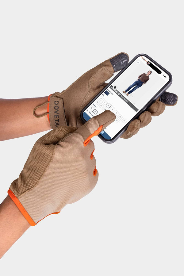 Woman wearing Dovetail Workwear Multi-Purpose Work Gloves in Light Kodiak while using a smartphone, showcasing touchscreen-compatible fingers and the glove's functional design