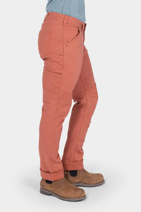 Side view of a woman wearing Dovetail Workwear GO TO™ Pants in Terracotta with visible tool loop, nested pockets, and reinforced knee, paired with brown boots