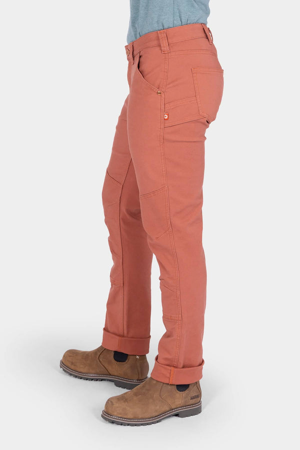 Side view of a woman wearing Dovetail Workwear GO TO™ Pants in Terracotta with cuffed legs and visible tool loop, paired with brown boots