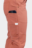 Side view of a woman wearing Dovetail Workwear GO TO™ Pants in Terracotta, displaying nested pockets and tool loop with phone in pocket