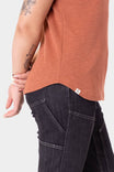 Side view of a woman wearing the Terracotta Old School Summer Henley Shirt by Dovetail Workwear with dark jeans, showing the breathable cotton blend waffle knit fabric and button-front placket