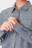 Detail of a woman's hands wearing the Dovetail Workwear Givens Long Sleeve Summer Work Shirt in Indigo Blue, showcasing the contrast inner cuffs and button chest pocket