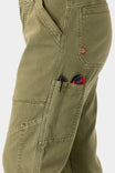 Close-up detail of the Range Crop Pant in Kelp Green by Dovetail Workwear, highlighting the bellowed front pocket with tools and the brand's red label