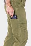 Woman wearing Dovetail Workwear Range Crop Pant in Kelp Green, demonstrating the bellowed front pocket while holding a phone