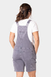 Back view of Dovetail Workwear's Utility Short Overalls in Driftwood Grey, showing nested side pockets, tool loops, and relaxed fit garment-washed denim shortalls on a woman