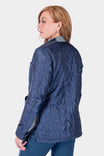 Back view of a woman wearing the Dovetail Workwear Durham Reversible Quilted Shirt Jac in Loden Green Plaid, showing the quilted texture and reinforced shoulders