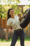 Rae Ripple x Dovetail Workwear Love Language T-Shirt in buttermilk worn by a woman holding a tire swing under hanging greenery