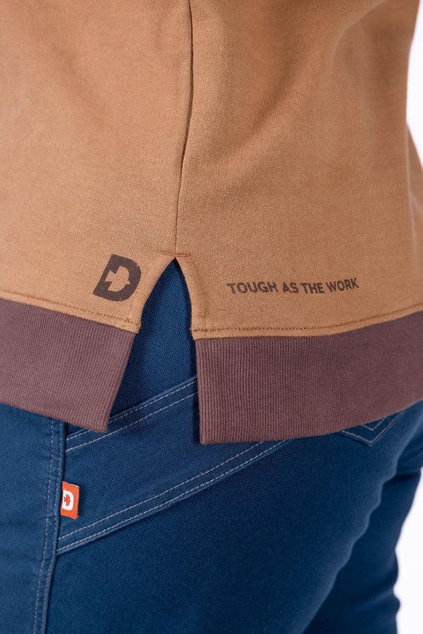 Detail view of the Dovetail Workwear GO TO™ Crew Sweatshirt in Saddle Brown showing the Dovetail graphic at hem and ribbed hem on a woman