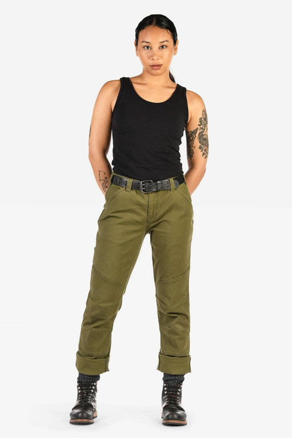 Dovetail Workwear GO TO™ Stretch Canvas Pant in Kelp Green shown on a woman wearing a black tank top, black lace-up boots, and a tool belt, standing against a white background