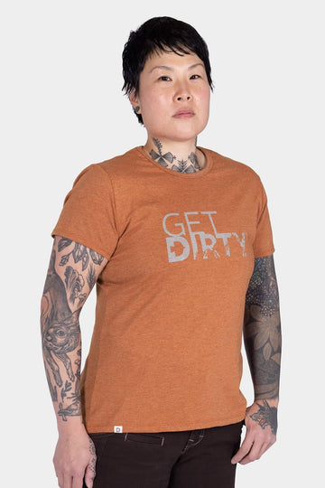 Woman wearing Dovetail Workwear GO TO "Get Dirty" Graphic Work Tee in rust orange with white front graphic against white background