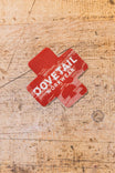 Dovetail Workwear x NoSo DIY Repair Patches displayed on a wooden surface, showing the peel-and-stick fabric patches for gear repair