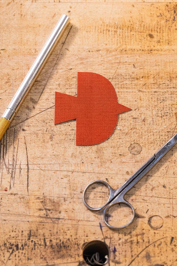 Dovetail Workwear x NoSo DIY Repair Patches displayed on cork surface with crafting tools, featuring paprika orange patch alongside scissors and brush
