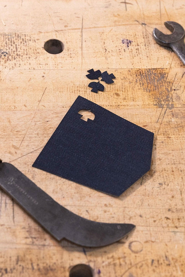 Black Denim Pocket Patch from Dovetail Workwear x NoSo DIY Repair Patches displayed on wooden workbench with tools and fabric scraps