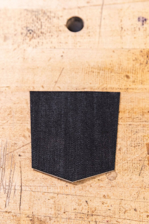 Black Denim Pocket Patch from Dovetail Workwear x NoSo DIY Repair Patches displayed on cork surface