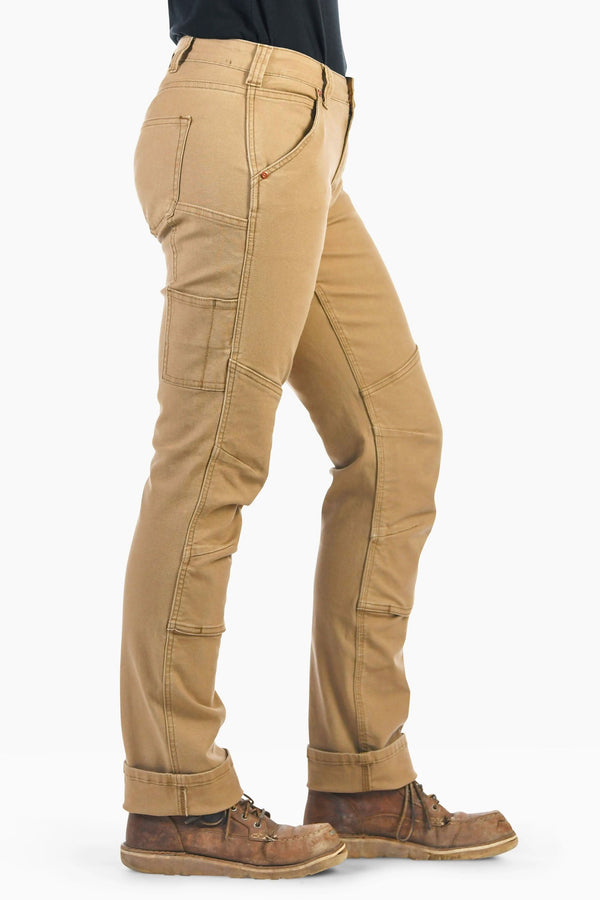 Side view of a woman wearing Dovetail Workwear GO TO™ Stretch Canvas Pant in Sawdust Brown, featuring nested pockets, tool loop, and reinforced knee