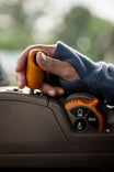 Woman wearing John Deere X Dovetail Workwear Early Bird Hoodie in Steel Blue, showing thumbhole detail and front pocket while holding work equipment outdoors