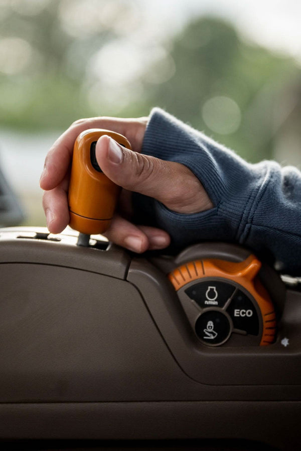 Woman wearing John Deere X Dovetail Workwear Early Bird Hoodie in Steel Blue, showing thumbhole detail and front pocket while holding work equipment outdoors