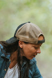 Side view of a woman wearing the Dovetail Workwear Embroidered Shop Cap in blue/black denim with khaki mesh, showing the adjustable back closure and breathable mesh panels