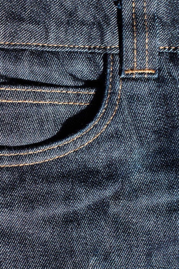 Close-up detail of the Dovetail Workwear DX Bootcut Pant in FR Denim, showing the signature stitching and iconic bootcut silhouette in indigo denim