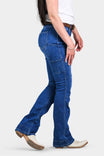 Side view of a woman wearing Dovetail Workwear's DX Bootcut Pant in Blue Sky Denim, showcasing the bootcut silhouette, nested pockets, and tool loop detail