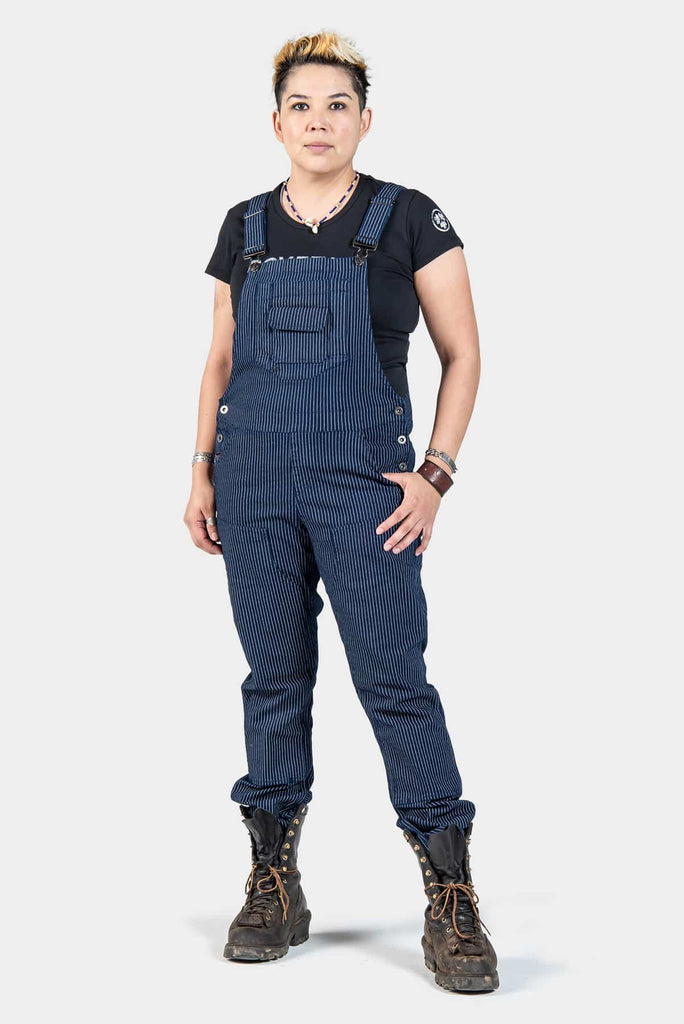 Freshley Overalls in Wabash Stripe by Dovetail Workwear displayed on a woman wearing a black tee, featuring striped denim with flex suspenders and reinforced knees