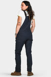 Back view of a woman wearing Dovetail Workwear's Freshley Drop Seat Overalls in Navy Canvas with reinforced knees and cargo pockets
