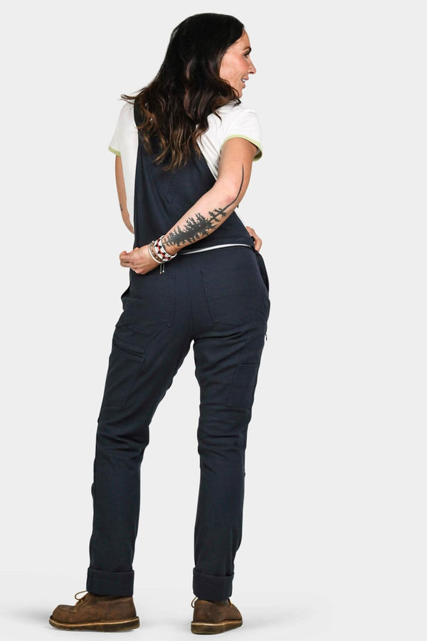 Back view of a woman wearing Dovetail Workwear's Freshley Drop Seat Overalls in Navy Canvas, showcasing the fit and reinforced construction details