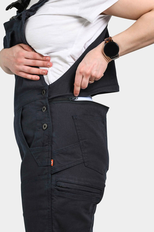 Detail shot of the hidden zip drop seat feature on Dovetail Workwear's Freshley Drop Seat Overalls in Navy Canvas, demonstrated by a woman opening the back zipper