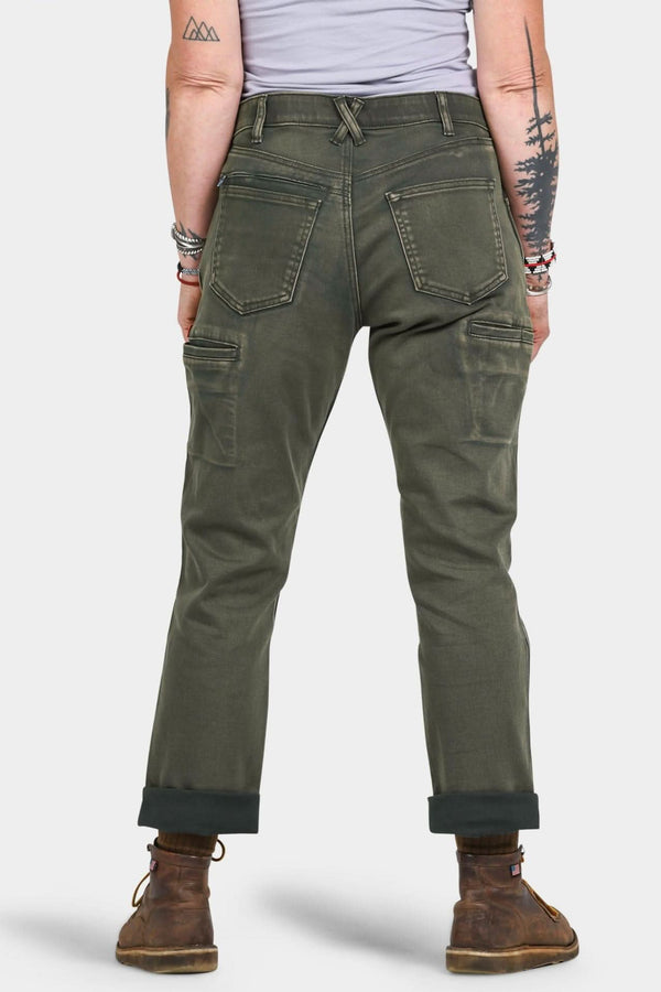 Back view of a woman wearing Dovetail Workwear's Shop Pant in Olive Green Denim, showing cargo pockets, high-rise waist, and rolled cuffs with brown boots