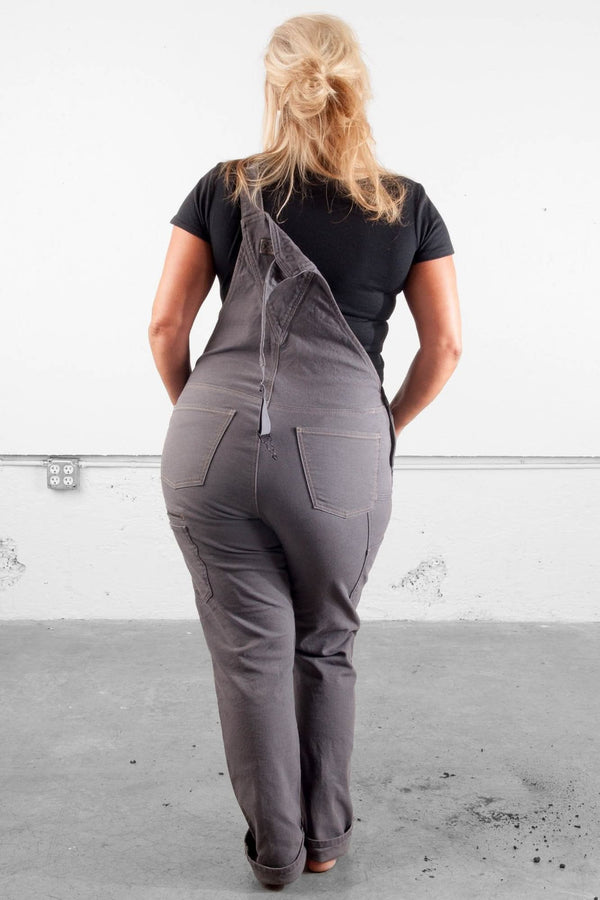 Back view of a woman wearing Dovetail Workwear Freshley Overalls in Grey Canvas, showcasing the reinforced knees and nested pockets
