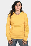 Woman wearing the Anna Pullover Hoodie in Yellow Oxide by Dovetail Workwear, featuring a V-neck, front zip pocket, and thumbhole cuffs