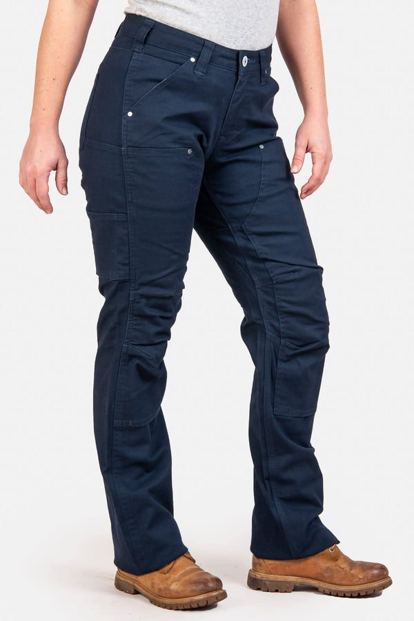 Anna Taskpant in Uniform Navy Canvas by Dovetail Workwear featuring reinforced knees, tool loops, and nested pockets, worn by a woman with brown boots