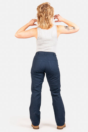 Back view of a woman wearing Dovetail Workwear's Anna Taskpant in Uniform Navy Canvas, highlighting the reinforced knees, nested pockets, and straight leg silhouette