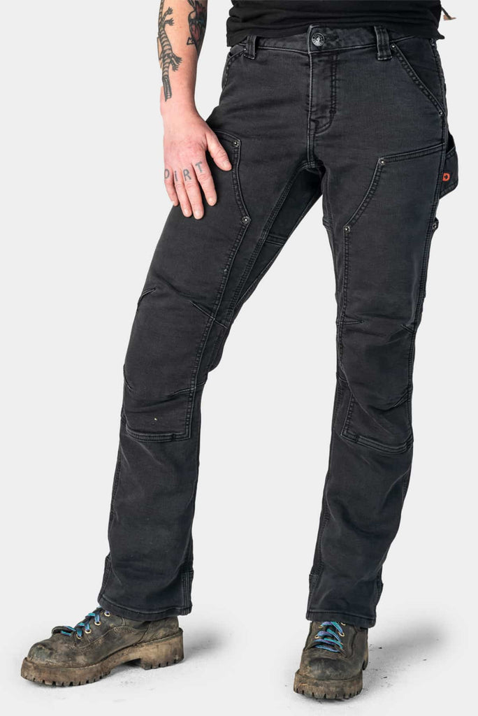 Black Stretch Thermal Denim Britt Utility Pant by Dovetail Workwear shown on a woman wearing work boots, featuring cargo-style pockets, reinforced knees, and articulated knee design