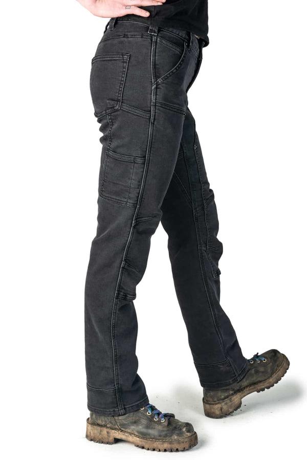 Side view of a woman wearing the Britt Utility Pant in Black Stretch Thermal Denim by Dovetail Workwear, featuring cargo-style pockets and reinforced knees