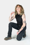 Britt Utility Pant in Black Stretch Thermal Denim by Dovetail Workwear, shown on a woman kneeling and displaying visible tattoos and work boots