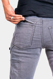 Back view of a woman wearing the Dovetail Workwear Britt Utility Pant in Grey Stretch Thermal Denim, highlighting the reinforced knee panel and cargo-style pocket detail