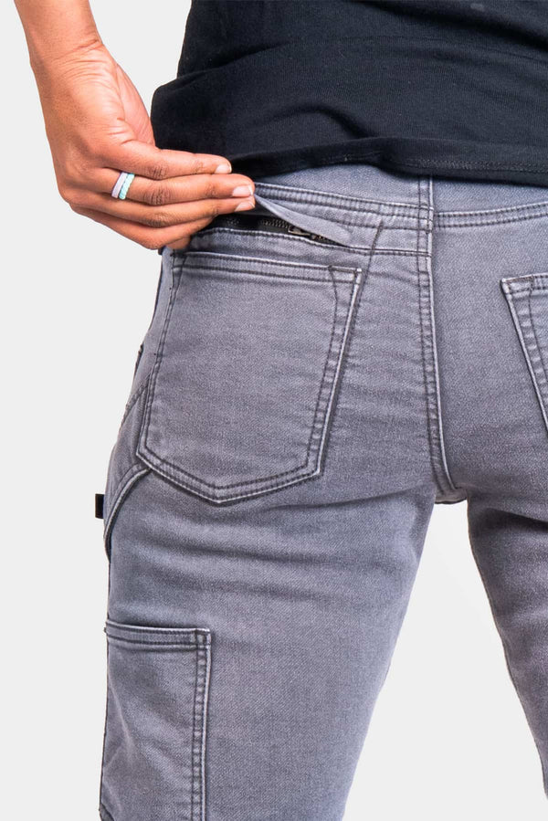 Back view of a woman wearing the Dovetail Workwear Britt Utility Pant in Grey Stretch Thermal Denim, highlighting the reinforced knee panel and cargo-style pocket detail