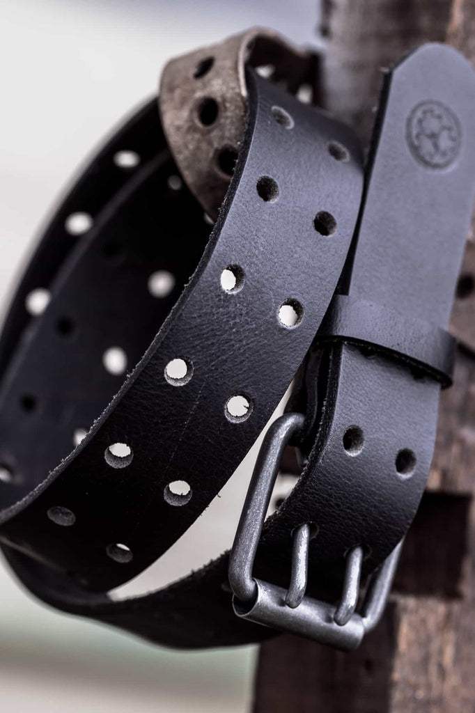 Detail shot of the Dovetail Workwear Double Pronged Work Belt in Black Tar, showing full-grain buffalo leather with debossed triple bird icon and double-pronged buckle