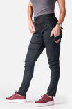Side view of a woman wearing Dovetail Workwear's Christa DIY Pant in Black Performance Modal, featuring visible zip pockets, reinforced knees, and a relaxed slim leg fit