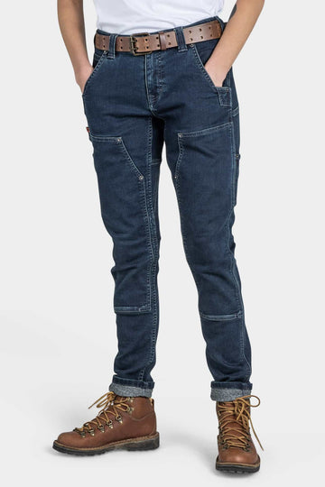 Maven X in Indigo Stretch Thermal Denim by Dovetail Workwear featuring reinforced knees, crotch gusset, and nested pockets, styled with brown lace-up hiking boots